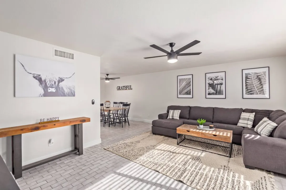 A warm and inviting living area with a comfortable sofa, coffee table, adjoining dining area, and tasteful wall art. The layout encourages both relaxing and entertaining, with ample space for guests to mingle.
