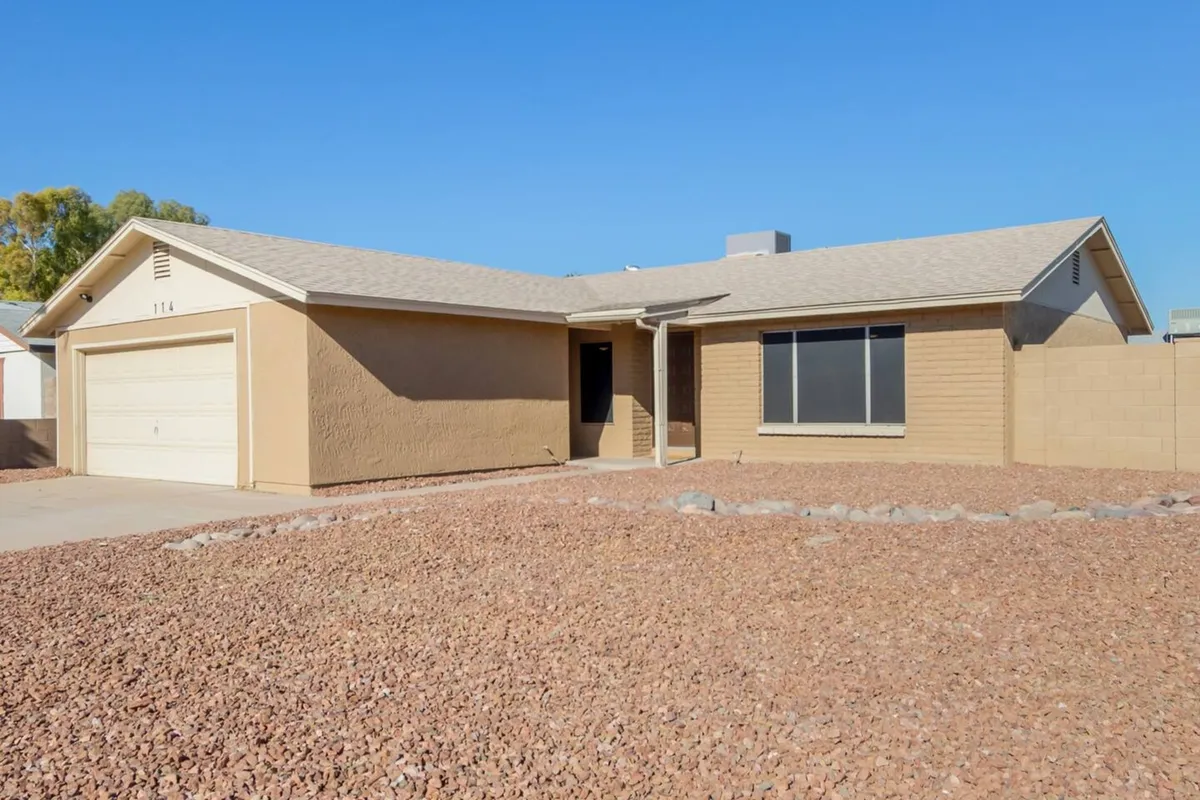 The home's front entrance with a modern door, large window, and distinctive rocky landscaping. The welcoming exterior is bathed in natural light, suggesting a warm, inviting atmosphere that would inspire arrival photos and showcase curb appeal.