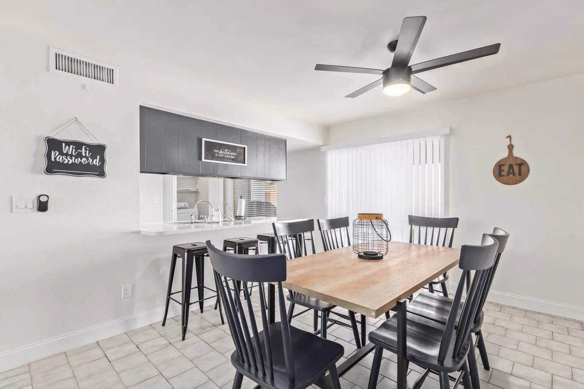 An inviting dining area featuring a modern table with black chairs, subtle wall art, and a ceiling fan overhead. The space is bright and welcoming, with thoughtful details that highlight the property's curated, Instagrammable aesthetic. The scene feels ready for family meals, gatherings, or productive work sessions.