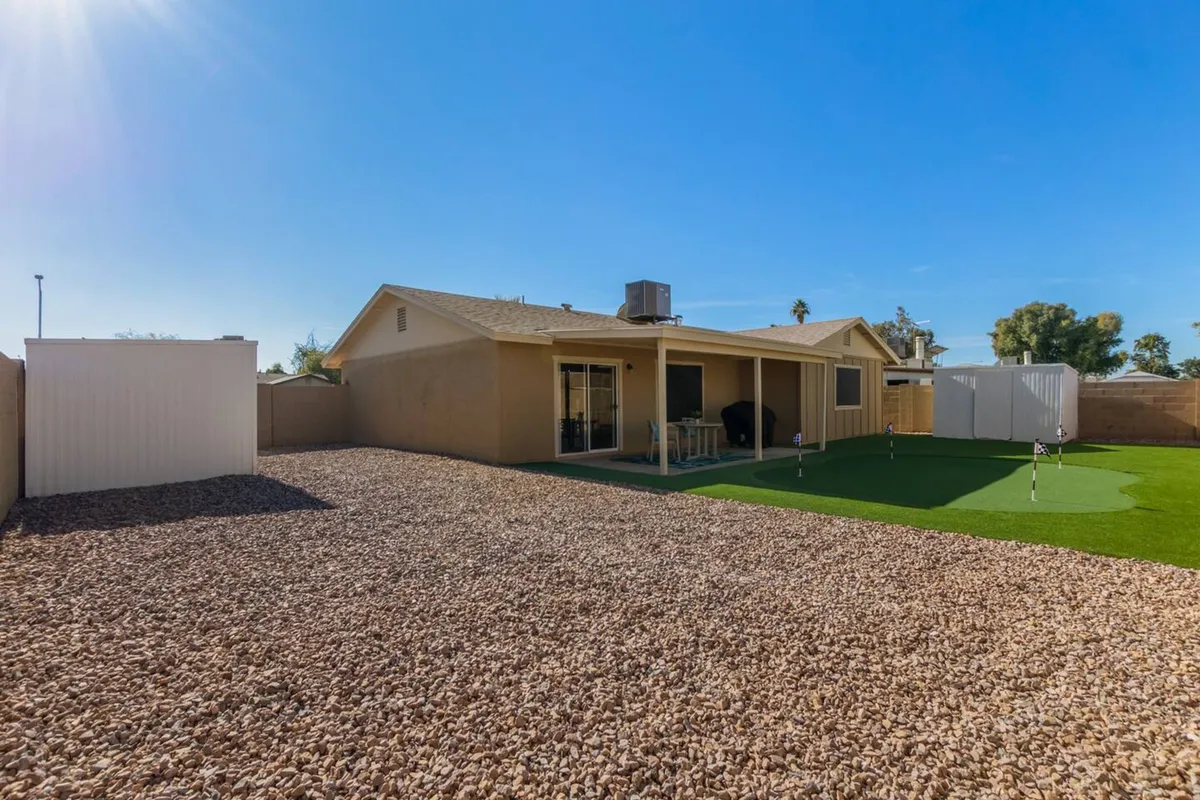 This exterior image displays a well-maintained lawn with patio furniture and rock landscaping, creating a tranquil space for morning coffee, outdoor work sessions, or evening relaxation. The overall vibe is inviting and serene, echoing the comfort and flexibility mentioned in the section.