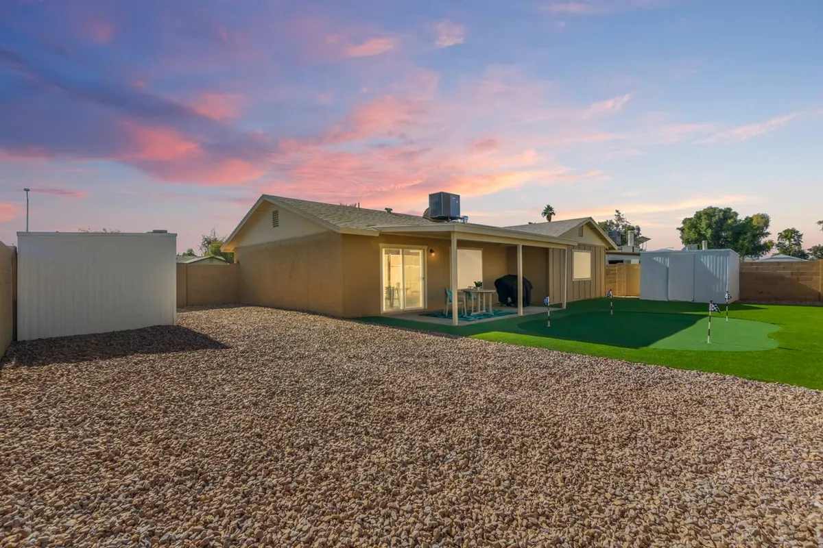 The image showcases the welcoming exterior of a spacious single-family home, framed by a lush, green lawn and an inviting patio area perfect for outdoor dining or relaxing. The open Arizona sky provides a serene backdrop, and the scene suggests ample space for gatherings, outdoor games, or simply soaking in the tranquil ambiance.